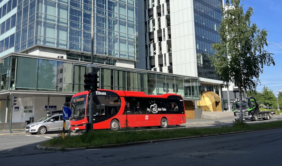 Bildet viser en rød buss i trafikken.